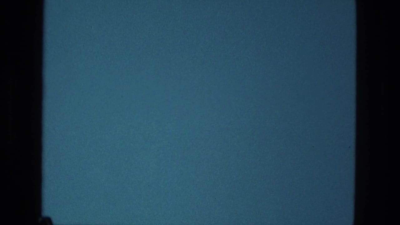 1979 Manaus 8mm frame showing a blue television-like field bordered by dark film edges, with grain and contact-sheet division visible.