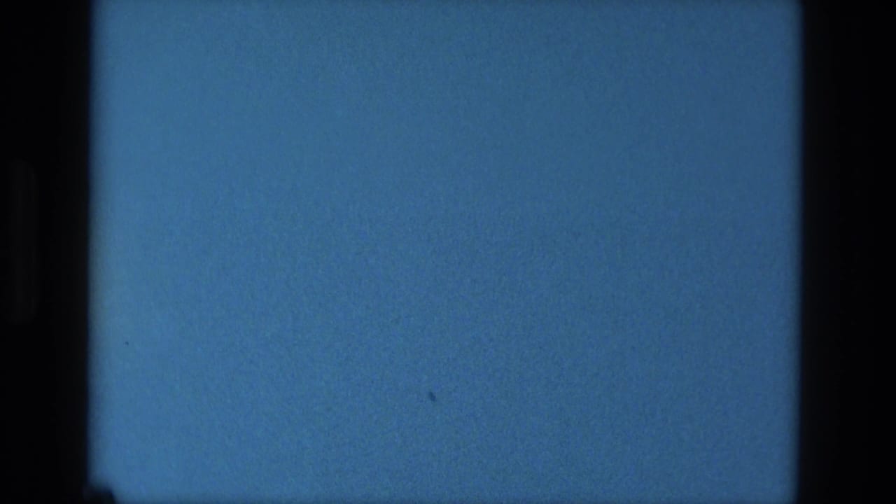 Blue-tinted 1979 8mm reel-end frame from Manaus with black film edges, grain, and small dust marks.