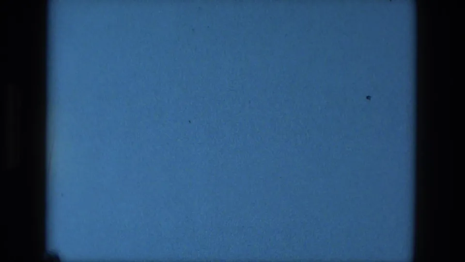Blue 8mm end-of-reel frame with black gate edges, subtle grain, and scattered dust marks from the Manaus home movie.