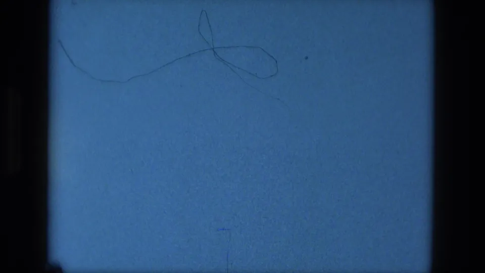 Final blue 8mm reel-end frame with dark borders, grain, dust, scratches, and a curved hair-like mark on the film surface.