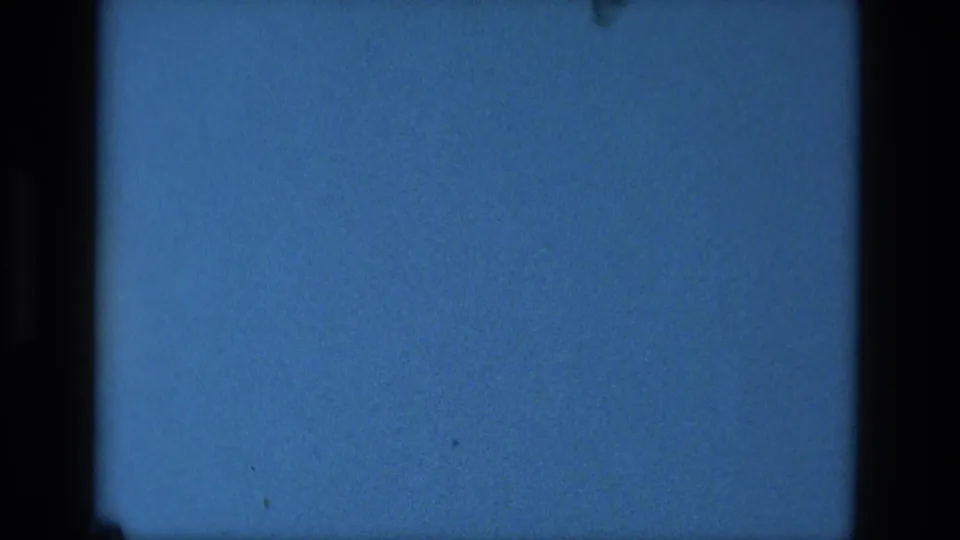 Blue 8mm frame from the 1979 Manaus clip, showing steady color, dark film edges, grain, and small dust marks.