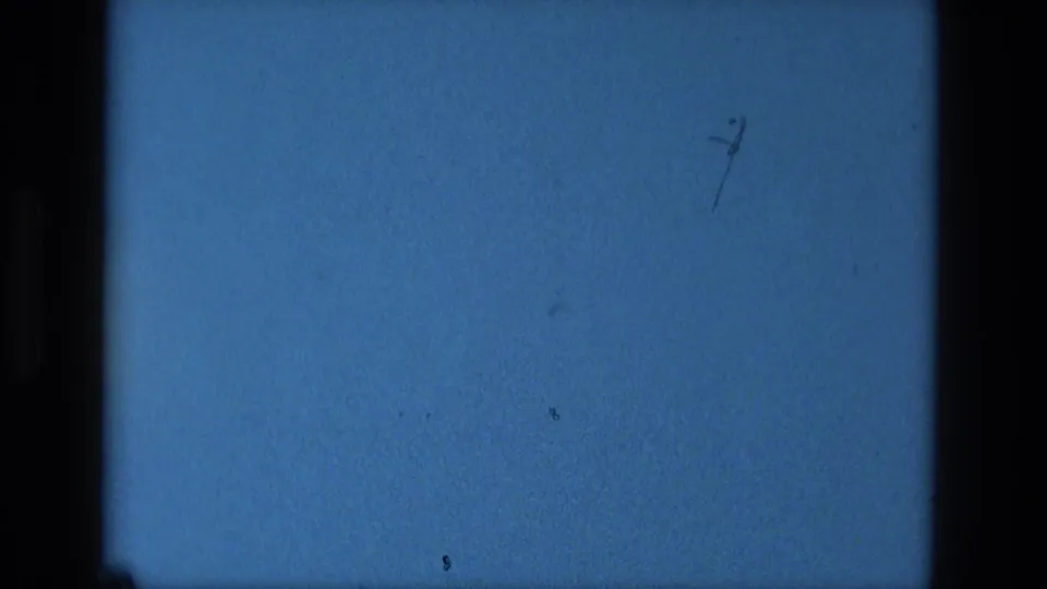 Static blue 8mm frame from the Manaus 1979 metadata, with dark borders, visible grain, dust, and a small scratch mark.