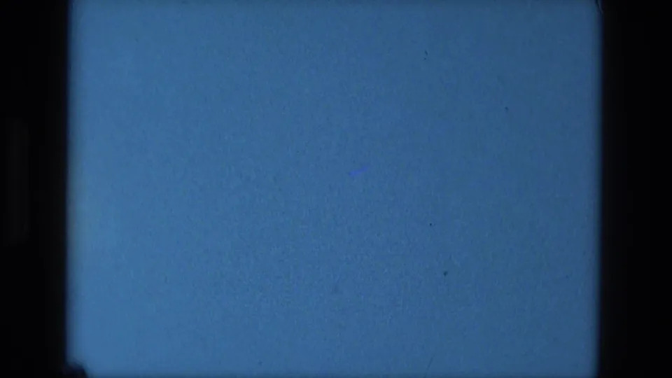 Final blue frame from the 1979 Manaus 8mm clip, remaining visually static with dark film edges, grain, and scattered specks.