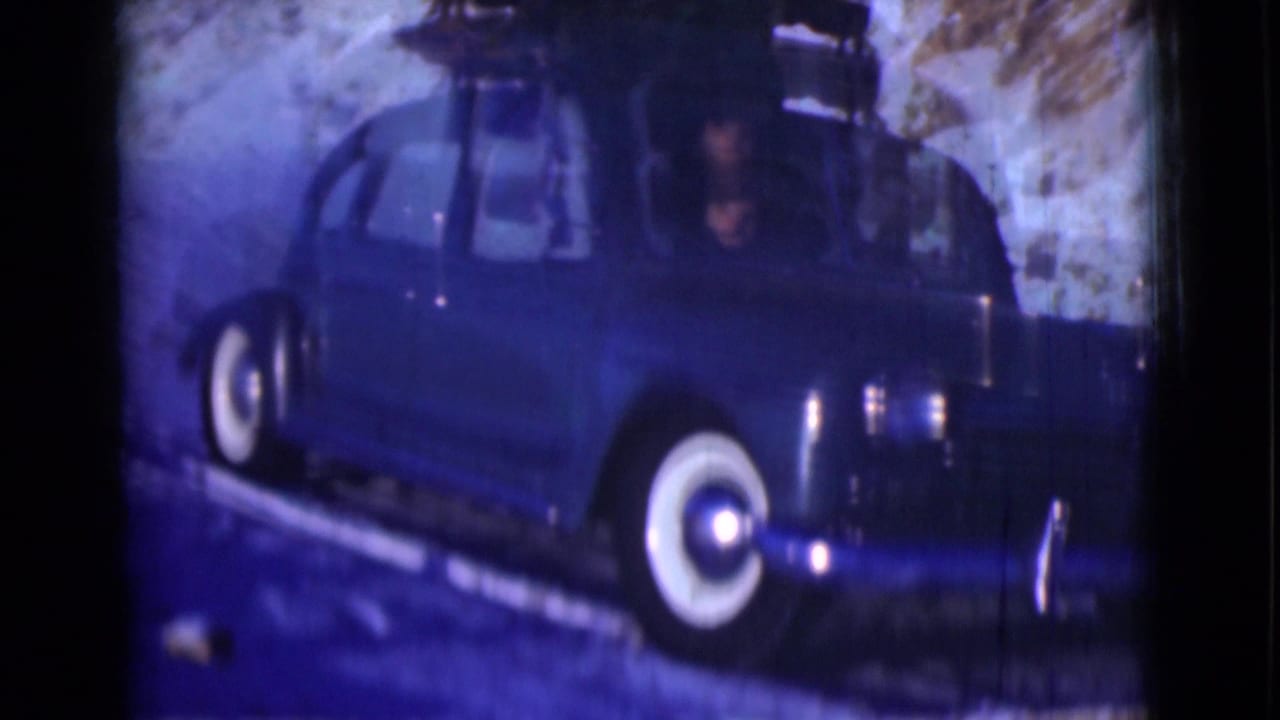 Blue 1940s sedan with whitewall tires on a snowy mountain road.
