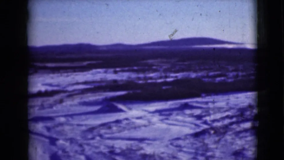 1946 Alaska home-movie view of snow-covered ground, low ridgelines, and distant mountains seen through 8mm film borders.