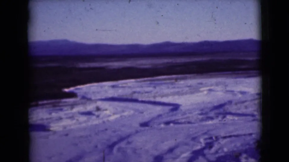 1946 Alaska frame with curving ice or water channels across snow-covered ground and a distant mountain ridge.