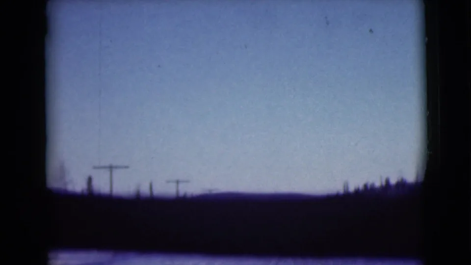1946 Alaska 8mm frame showing hazy sky, silhouetted land, and utility poles along a road-like horizon.