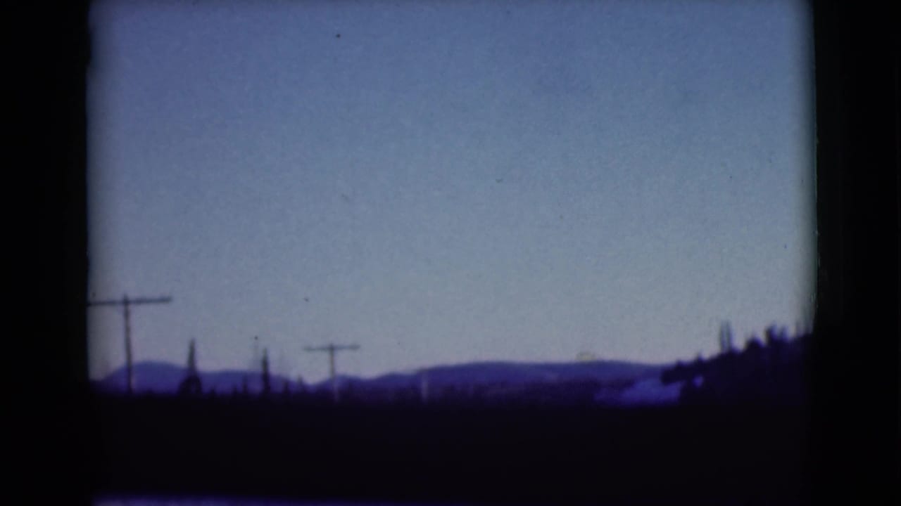 Distant hills and utility poles seen through a dark vehicle window frame.
