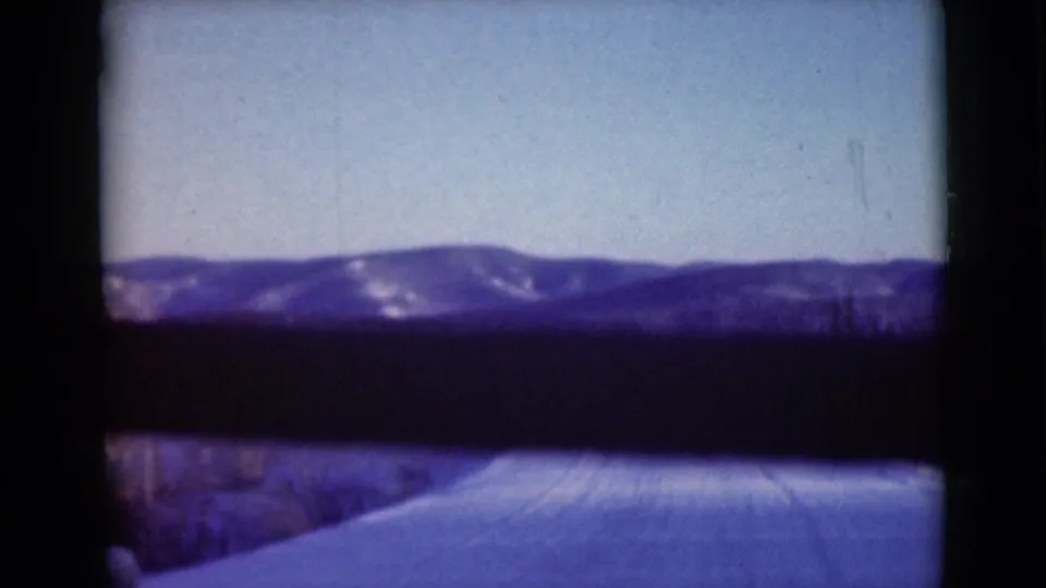 1946 Alaska 8mm frame showing a snowy road or open track below a distant mountain range, with visible gate edges.