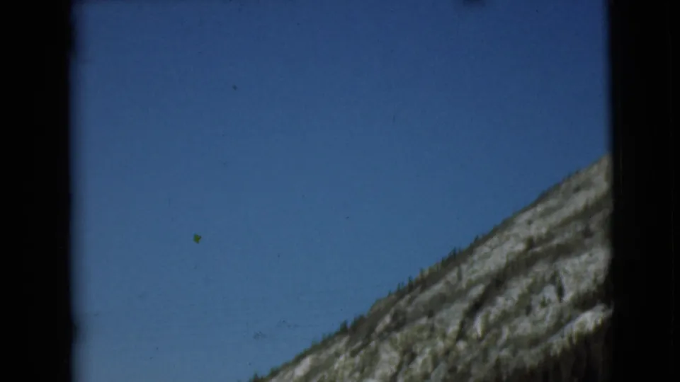 1946 Alaska 8mm frame showing a rugged slope with sparse vegetation beneath a broad blue sky.