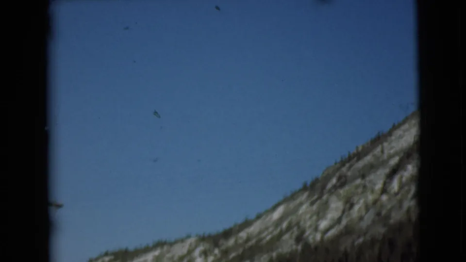 1946 Alaska 8mm frame of a slanted rocky hillside and open blue sky, with visible scan borders.