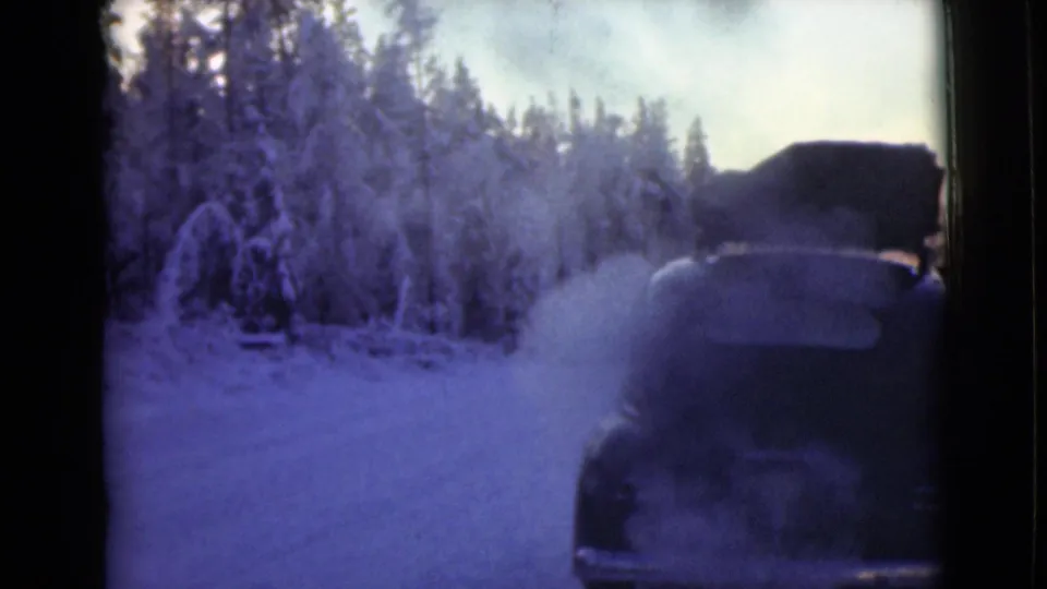 1946 Alaska frame with the rear of a car at the right edge, smoke drifting across a snowy forest road.
