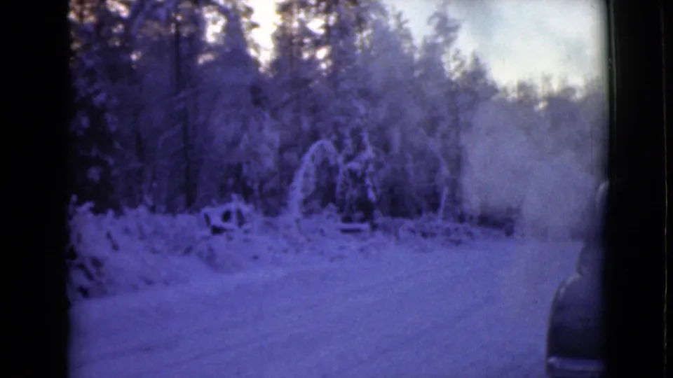1946 Alaska 8mm view of a snow-covered roadside forest with smoke drifting in from a partly visible car.