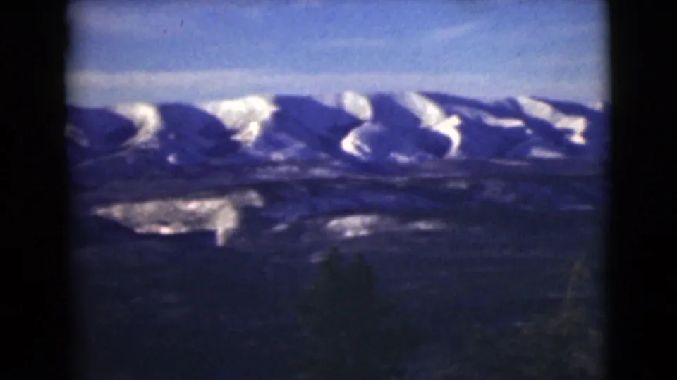 1946 Alaska 8mm view of snowy mountain ridges stretching across the horizon above a shadowed valley.