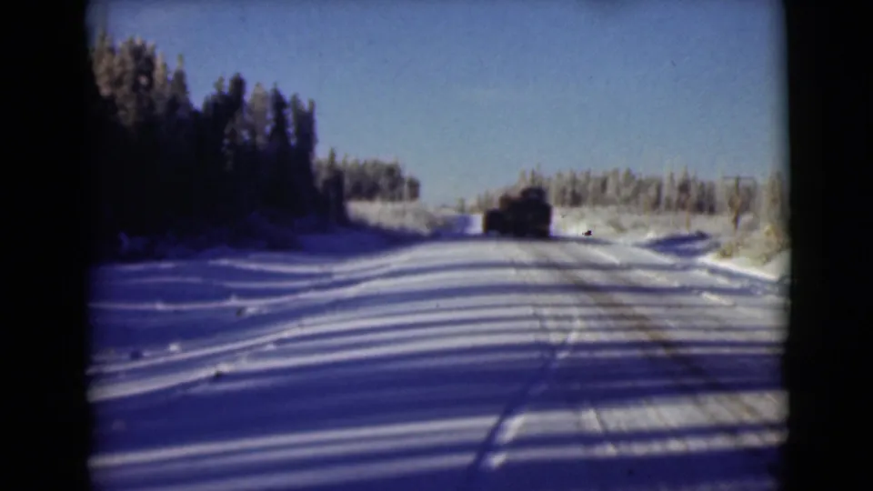 1946 Alaska 8mm frame showing a vehicle on a snow-covered rural road under clear sky.