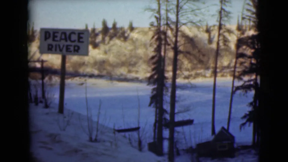 1946 Alaska 8mm frame showing the Peace River sign beside snow, trees, and a broad frozen or snow-covered river area.