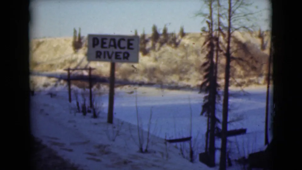 1946 Alaska 8mm frame centering the Peace River sign against a snow-covered riverbank, trees, and low hills.