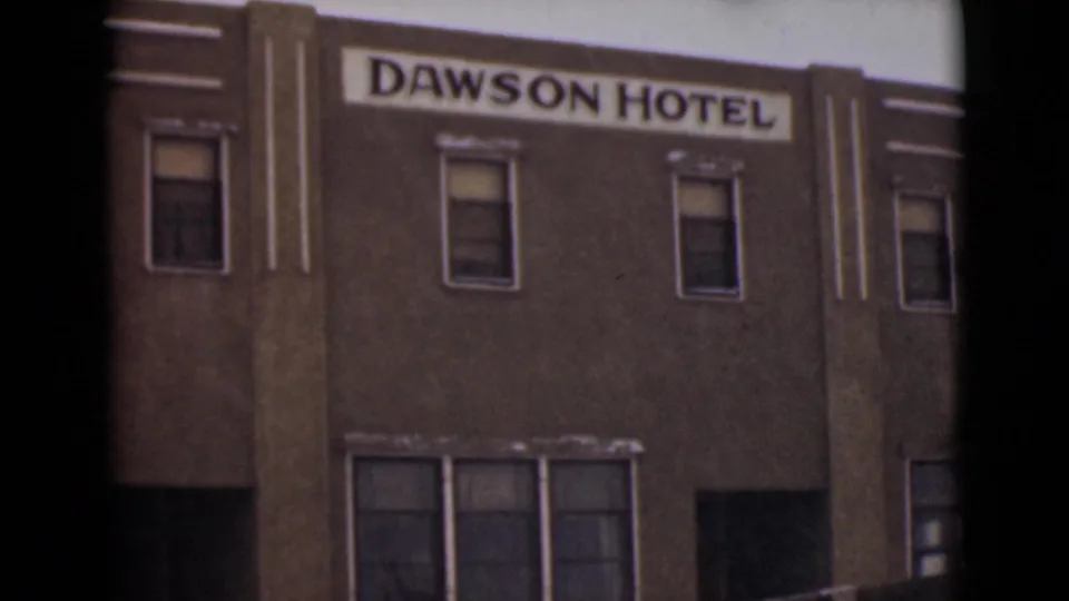 The final frame shows the Dawson Hotel sign on a multi-story town building, filmed in soft 8mm color during the Alaska sequence.