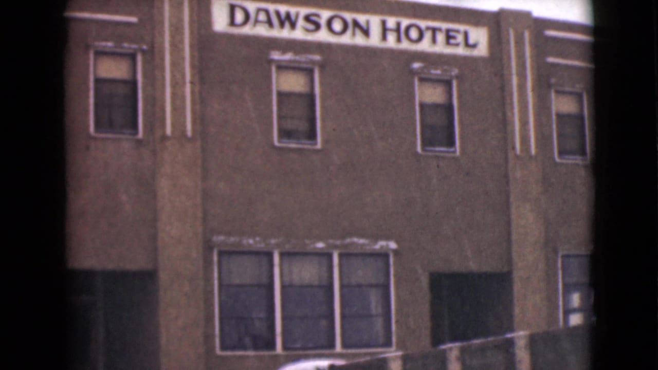 1946 Alaska 8mm frame showing the Dawson Hotel sign above a snowy hotel facade with windows and a truck partly visible at street level.