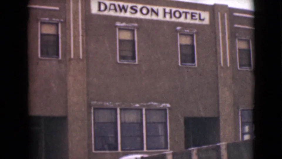 1946 Alaska 8mm frame showing the Dawson Hotel sign above a snowy hotel facade with windows and a truck partly visible at street level.