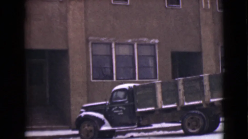 1946 Alaska 8mm frame showing a parked flatbed truck below the Dawson Hotel windows, with snow along the curb and facade.