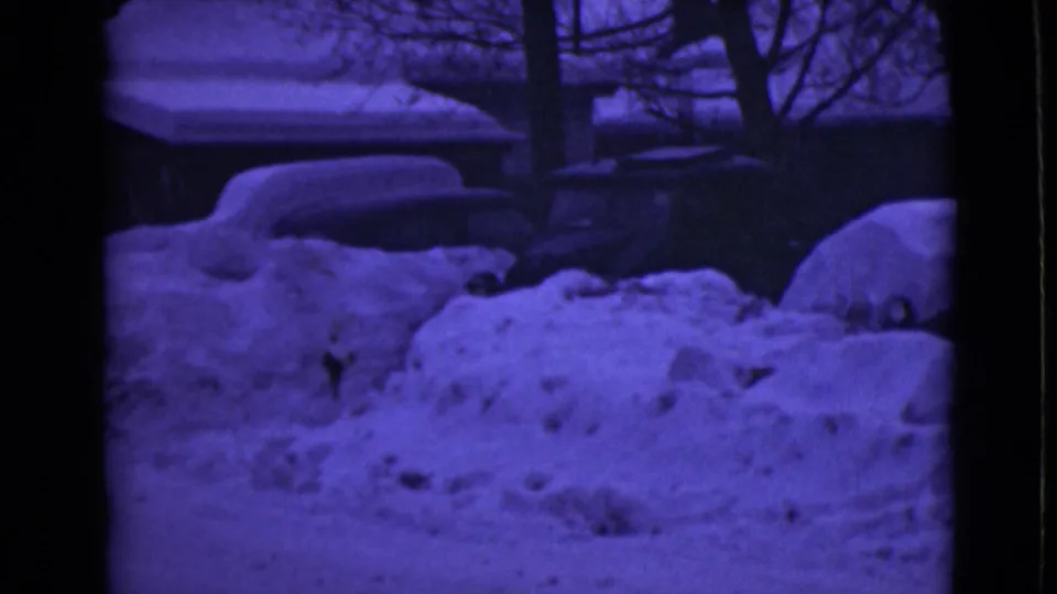8mm winter frame from Alaska in 1946 showing snowdrifts around vehicles, trees, and a dark roadside area.