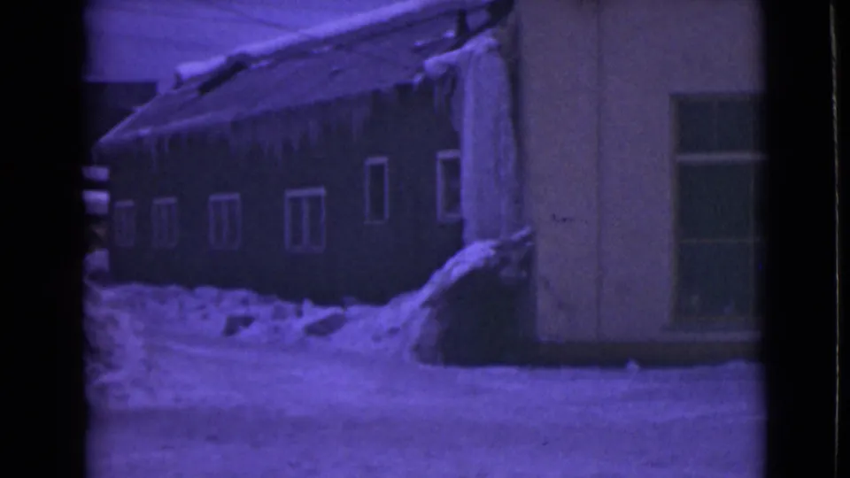 1946 Alaska 8mm frame of a house exterior bordered by deep snow and roofline icicles.