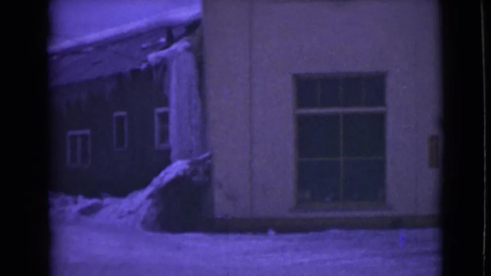 1946 Alaska 8mm frame showing a snow-covered building facade with a large window, icicles along the roofline, and a purple film tint.
