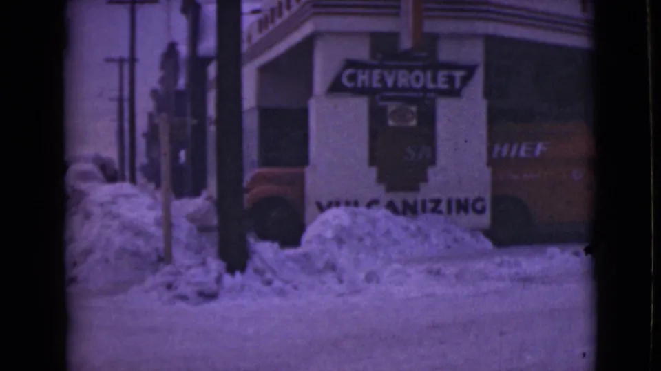 1946 Alaska storefront view with Chevrolet branding, vulcanizing service text, snowbanks, and a partial vehicle.