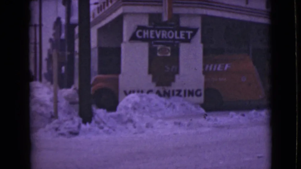 End frame of a 1946 Alaska street scene with Chevrolet storefront signage, snow piled at the curb, and part of a vehicle.