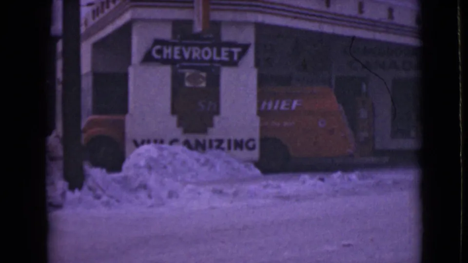 1946 Alaska street view with a red Chief van parked by a snowbank outside a building marked with Chevrolet signage.