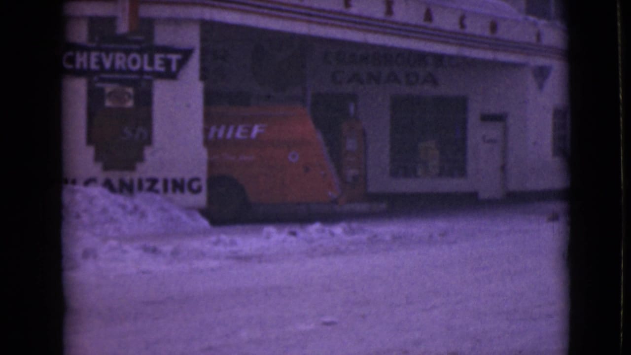 Red van parked outside a snowy storefront with Chevrolet and Canada signage.