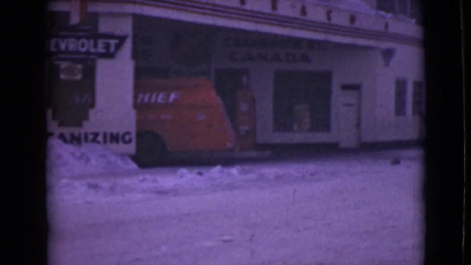 Soft 8mm winter view of a red van beside a storefront with partial Chevrolet and Canada signage.