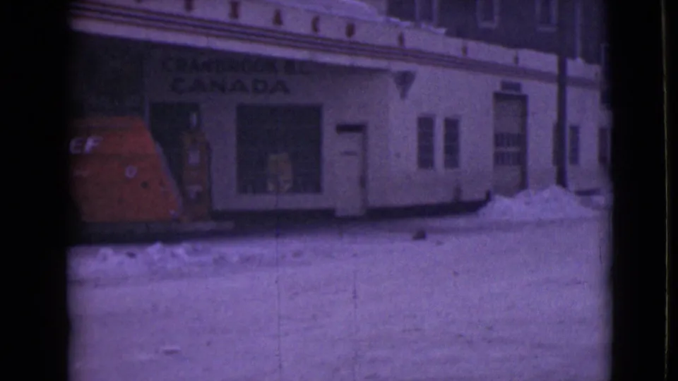 End frame of the 8mm clip with the red van partly cropped and storefront signage over a snowy street.
