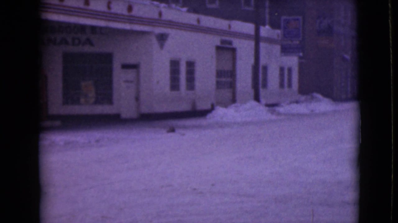 Snowy storefront frontage with Cranbrook Canada sign, window, doorway, and snowbanks along the building.
