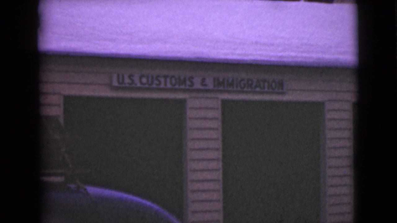 1946 Alaska 8mm frame showing a snow-covered U.S. Customs and Immigration wood building facade with a partial car at left.
