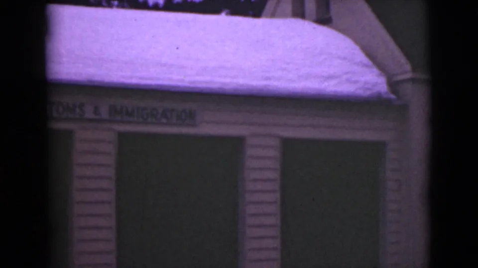 1946 Alaska 8mm frame with the U.S. Customs and Immigration facade partially cropped beneath a snow-covered roof.