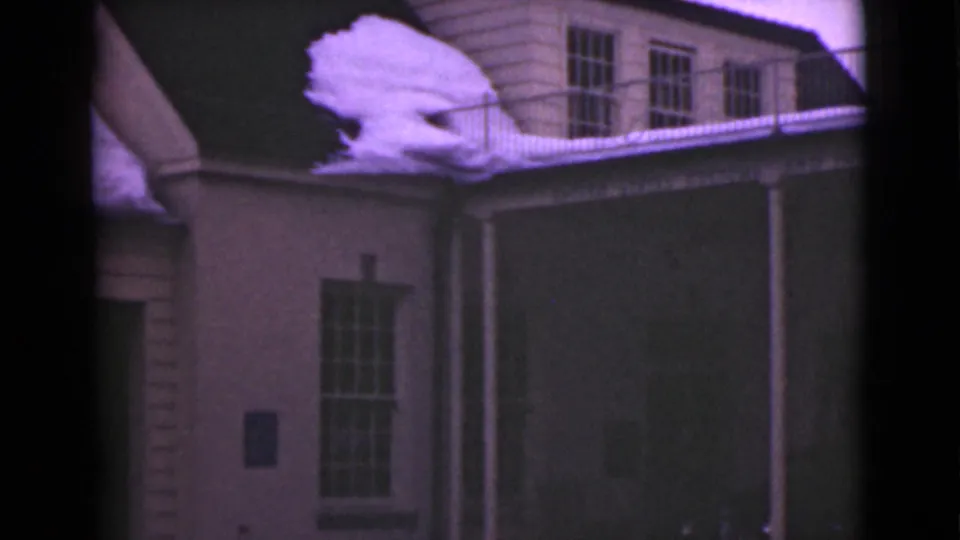 1946 Alaska 8mm frame ending on the building side with roof snow, railing, divided window, and a broad dark exterior wall panel.