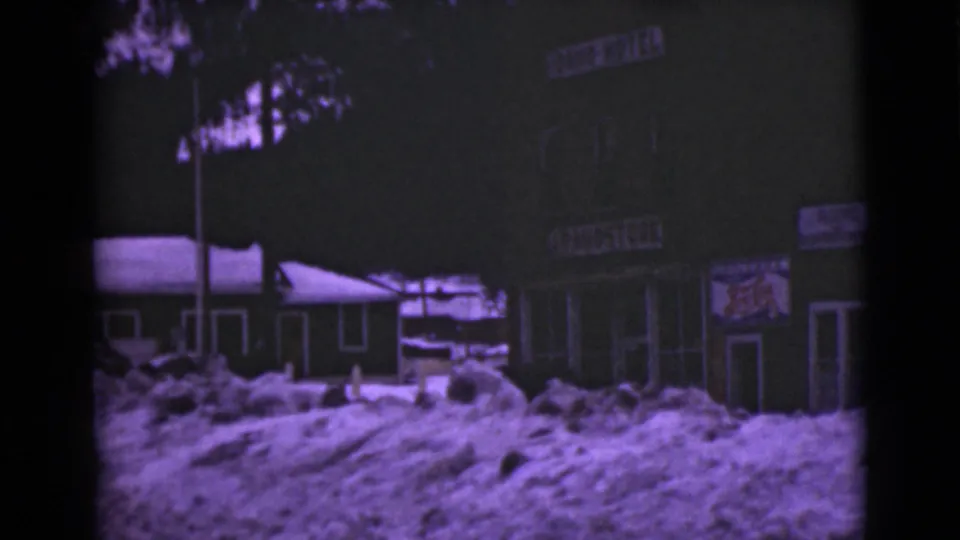 1946 Alaska view of a snowbound building frontage with Lion Hotel signage, doors, windows, and tree silhouettes.