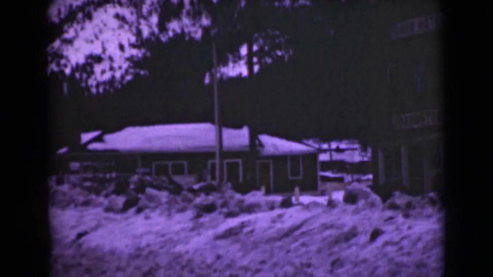 1946 Alaska frame showing snow piled before building exteriors, with the Lion Hotel sign partly visible near the right edge.