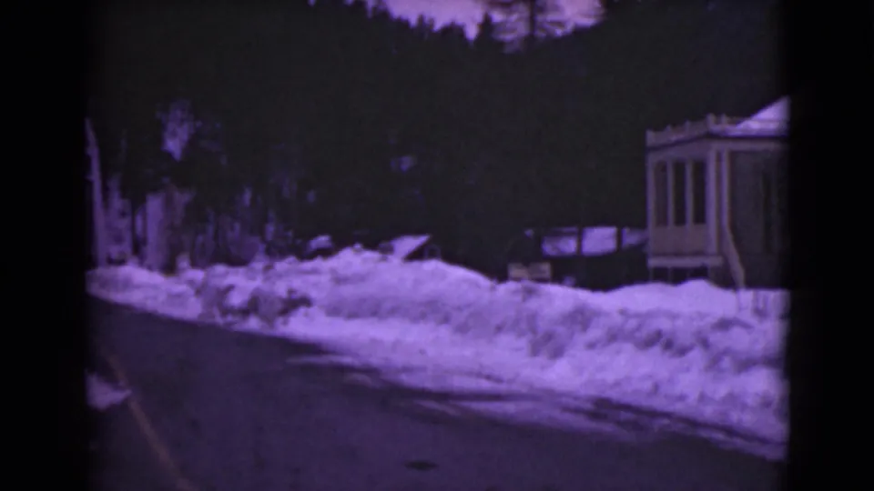 1946 Alaska 8mm frame showing a dark winter road, deep snowbanks, and a small wooden house along the route.