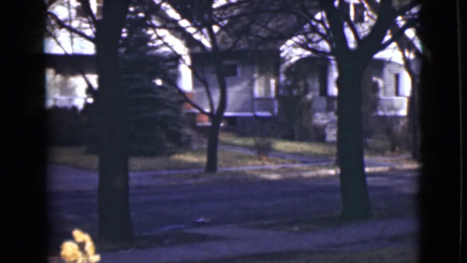 Final 1946 Alaska frame showing a quiet street and white houses partially blocked by dark vertical and horizontal foreground edges.