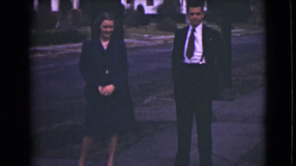 A 1946 Alaska frame shows the formally dressed couple closer together, facing the camera on a residential sidewalk.