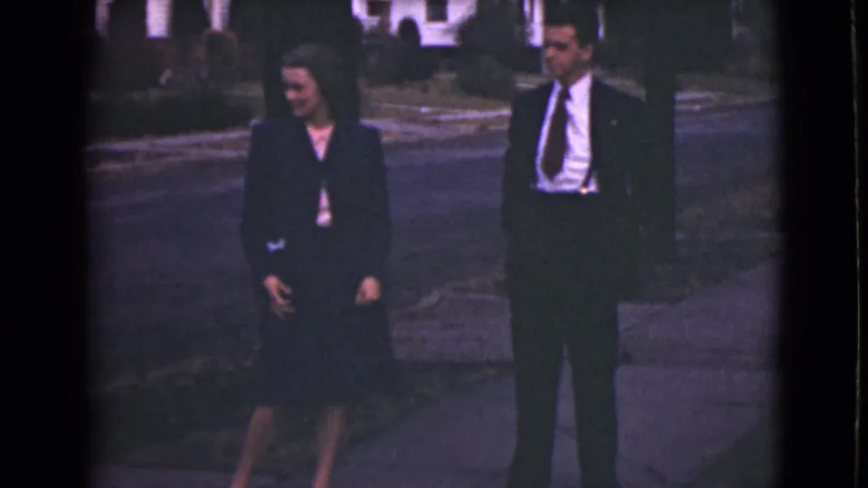 In the final frame, the woman glances downward and the suited man turns slightly toward her on the Alaska sidewalk.
