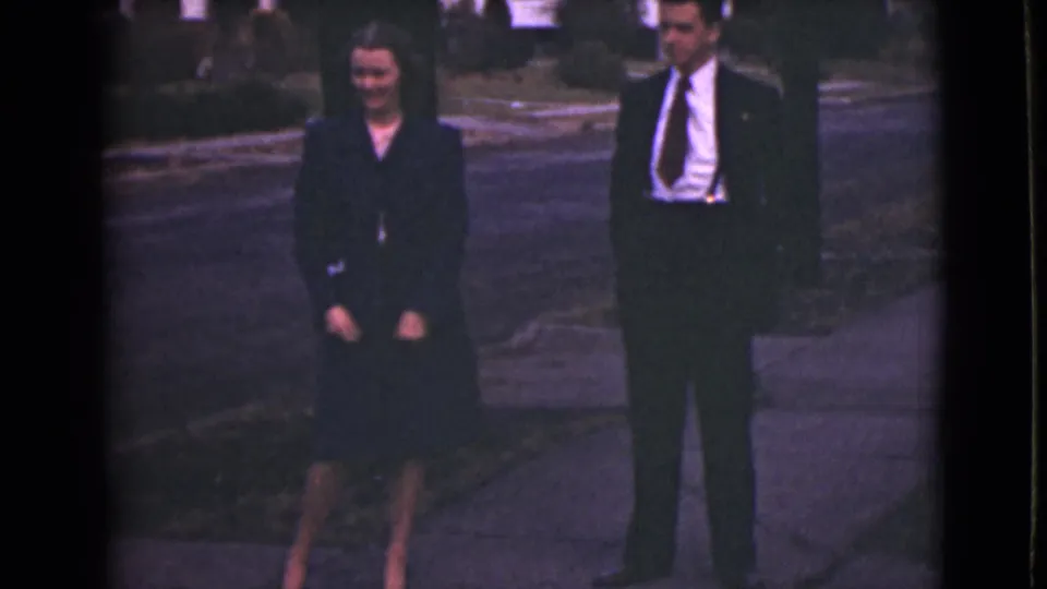 The woman and man face the camera on a sidewalk, with the supplied metadata placing the home movie in Alaska in 1946.