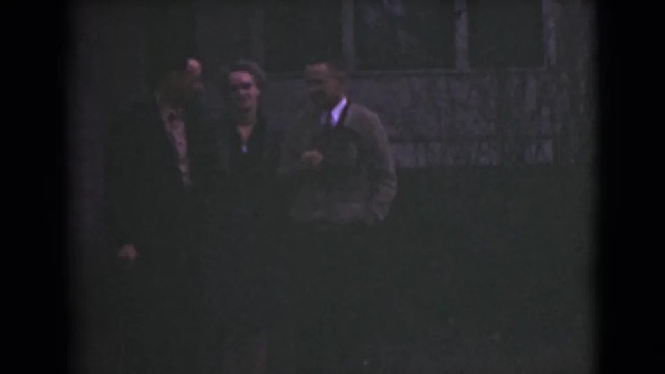 At the end of the clip, the three adults are still grouped in the shadowed 1946 Alaska scene, with grain and low exposure prominent.
