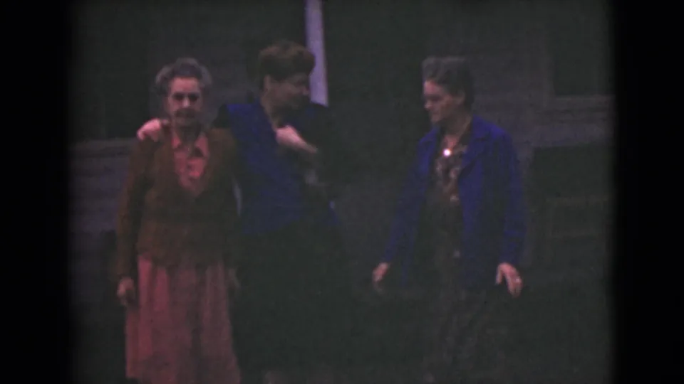 Three older women in 1940s Alaska walk and talk, with the center woman placing an arm around a companion.