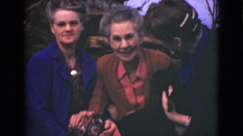 In this 1946 Alaska 8mm frame, three older women share a close laughing moment, with hands gathered near the center of the frame.
