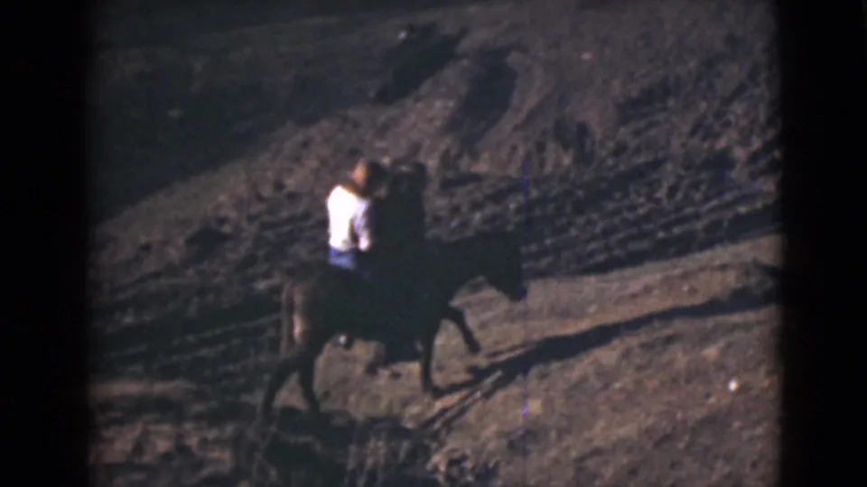 A rider on horseback crosses a rugged dirt hillside in 1946 Alaska home-movie footage, seen from a distance.