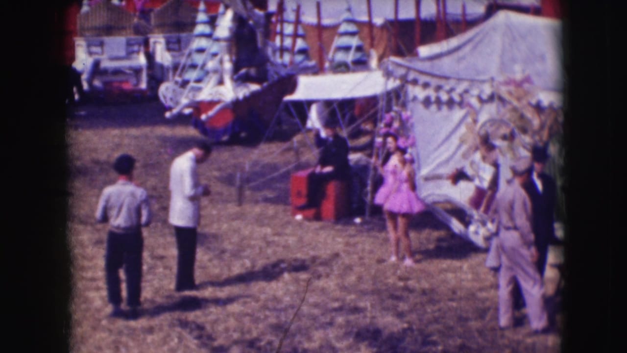 Photographers and visitors near circus tents as a woman in purple poses on the grounds.
